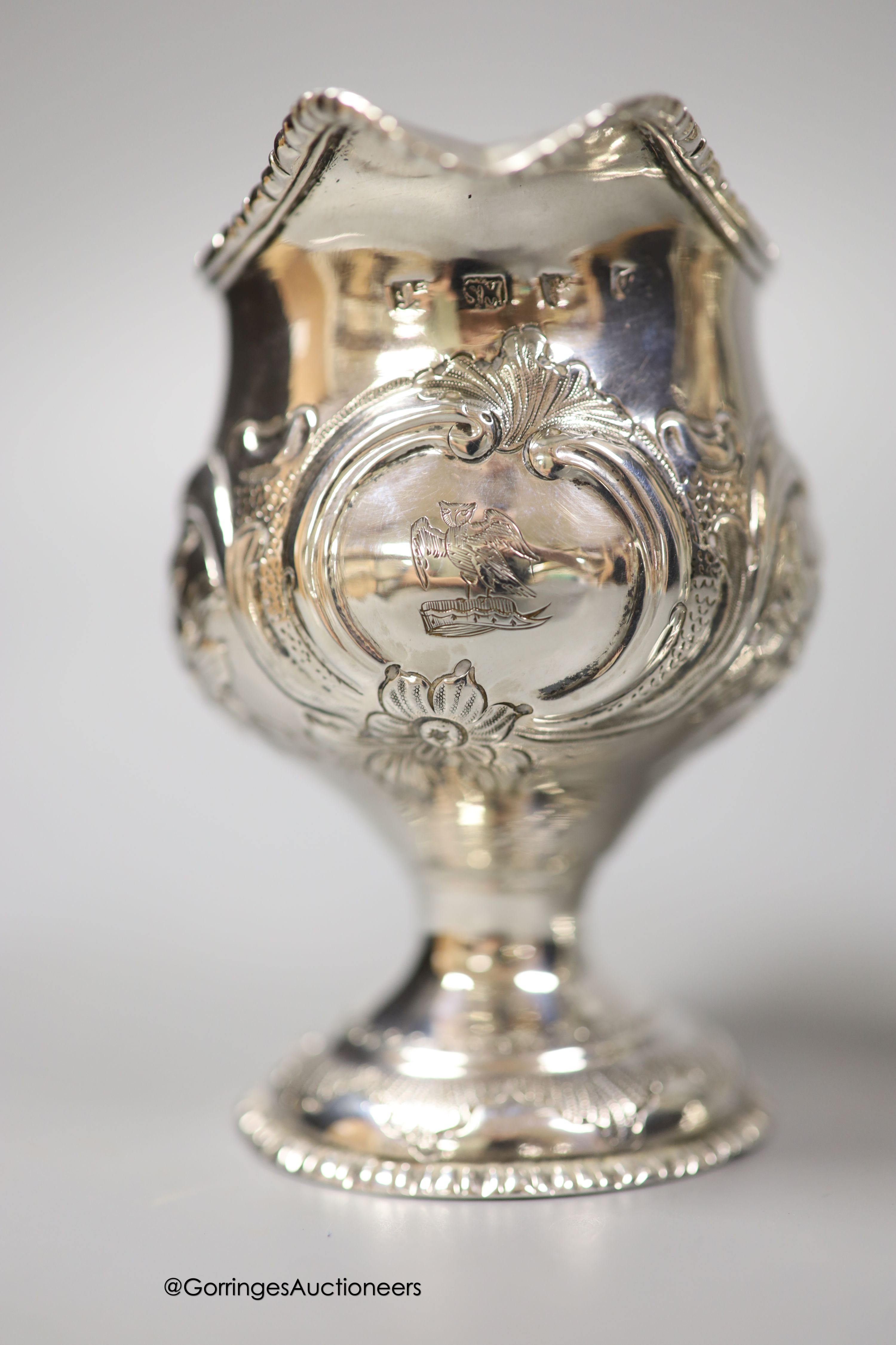 A George III silver inverted pear shaped cream jug, with later embossed decoration, marks rubbed, 9.7cm and a later cream jug, gross 210 grams.